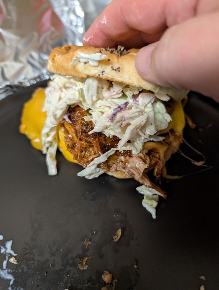 Pulled pork sandwich with melted cheddar cheese and coleslaw, on a toasted onion roll