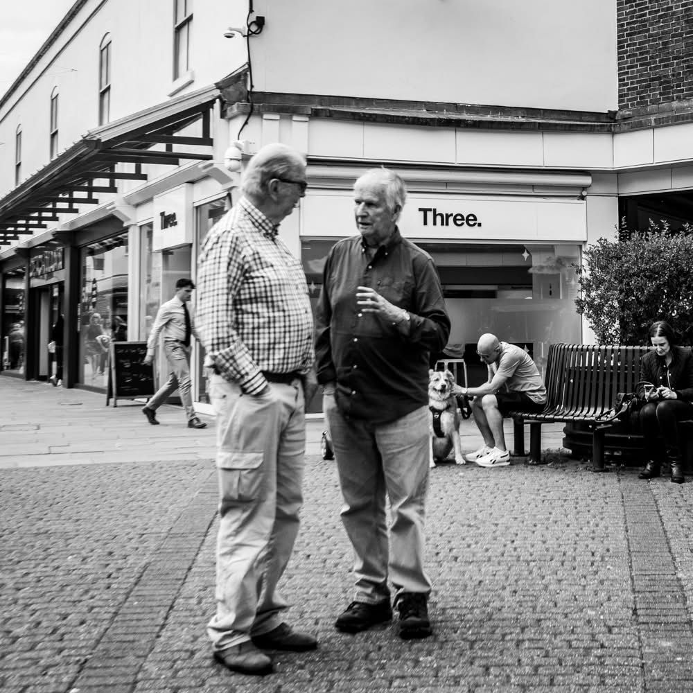 Two gentlemen in animated conversation in the street. Black and white photo 