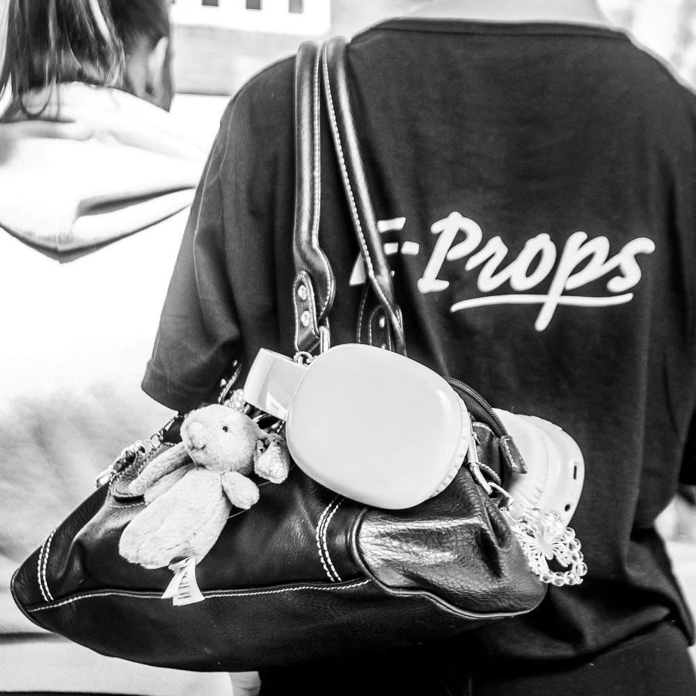 A close up of a persons shoulder bag with several bangles attached to it. Black and white photo 