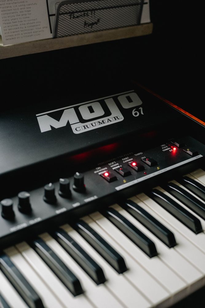 A color photograph of a Crumar Mojo 61 electric organ by a window.