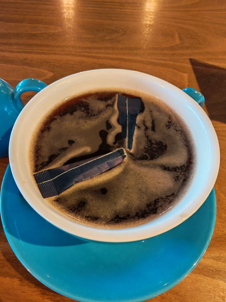 A cup of coffee with an open ugar sachet in it 