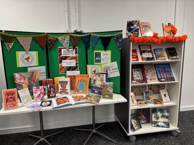 A photo of a table covered in books all about South Asian Heritage and decorated with posters about South Asian Heritage month.