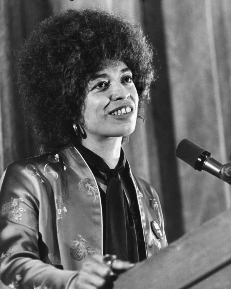 Angela Davis picture of her speaking at a podium.