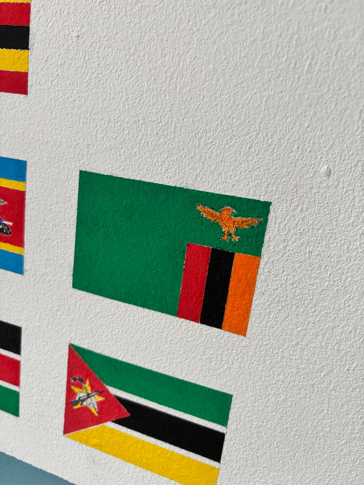 Full-colour, to-scale, hand-painted flag of Zambia, above the flag of Mozambique