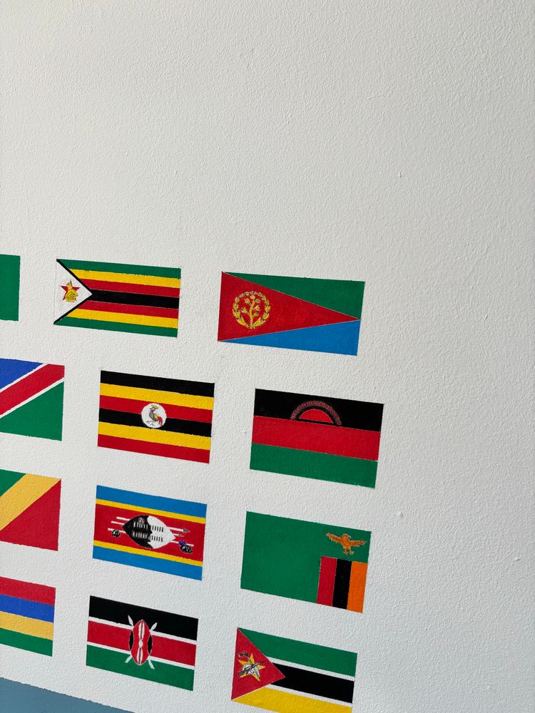 The fully-painted flag of Eritrea. Also in the photo are the flags of Zimbabwe, Uganda, Malawi, Eswatini, Zambia, Kenya, and Mozambique. 