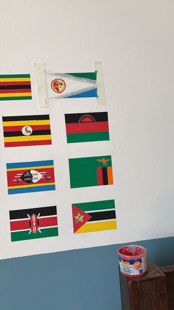The partly-painted flag of Eritrea. Also in the photo are the flags of Zimbabwe, Uganda, Malawi, Eswatini, Zambia, Kenya, and Mozambique. 