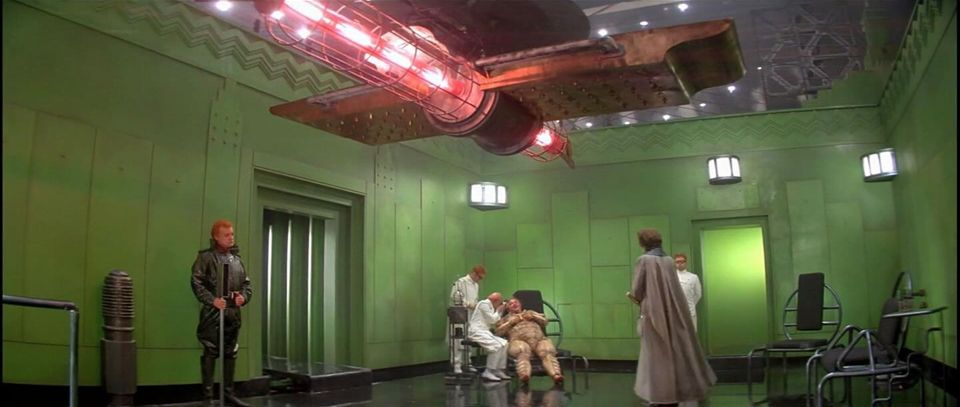 More pit than room, its walls sicklied over with a lurid green, its floor spotless and shining and black as a heart plug, this Giedi Prime interior is illuminated by the caged glare of a large red industrial lamp.  In the center, a fat old autocrat is attended by his slavish observants.  Fear of his whims, his caprices and cruelties, are the card and carrier of their loyalty, and may be read in every face but his.