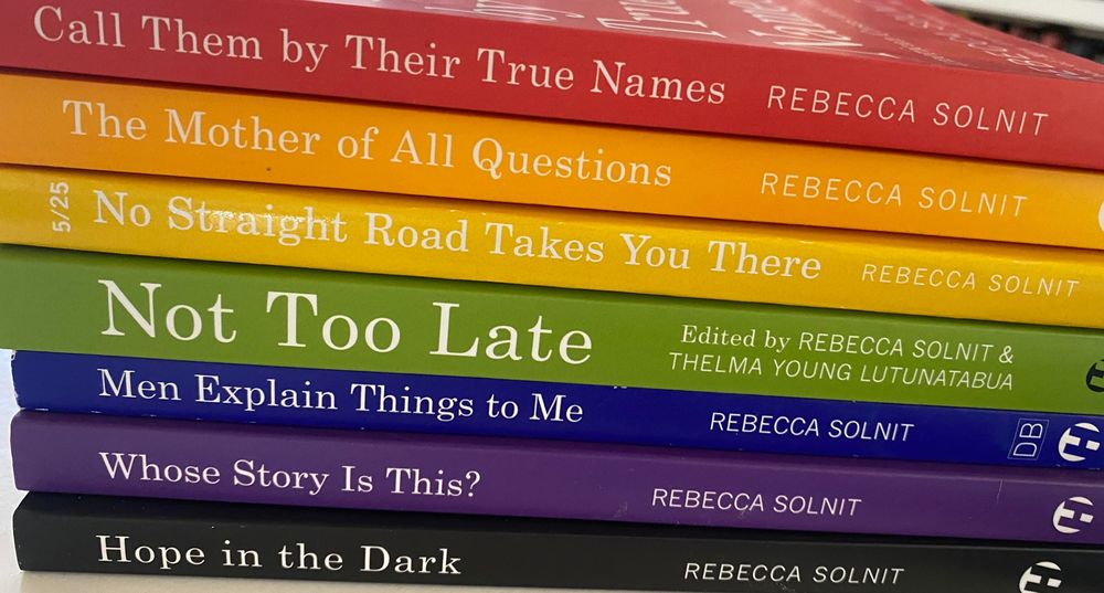 Image of seven of my books with Haymarket, Hope in the Dark (black), Whose Story Is This (violet), Men Explain Things to Me (blue), Not Too Late: Changing the Climate Story from Despair to Possibility, coedited with Thelma Young Lutunatabua and including 20 amazing writers from around the world (green), No Straight Road Takes You There (yellow), The Mother of All Questions (orange), and Call Them By Their True Names (red). 