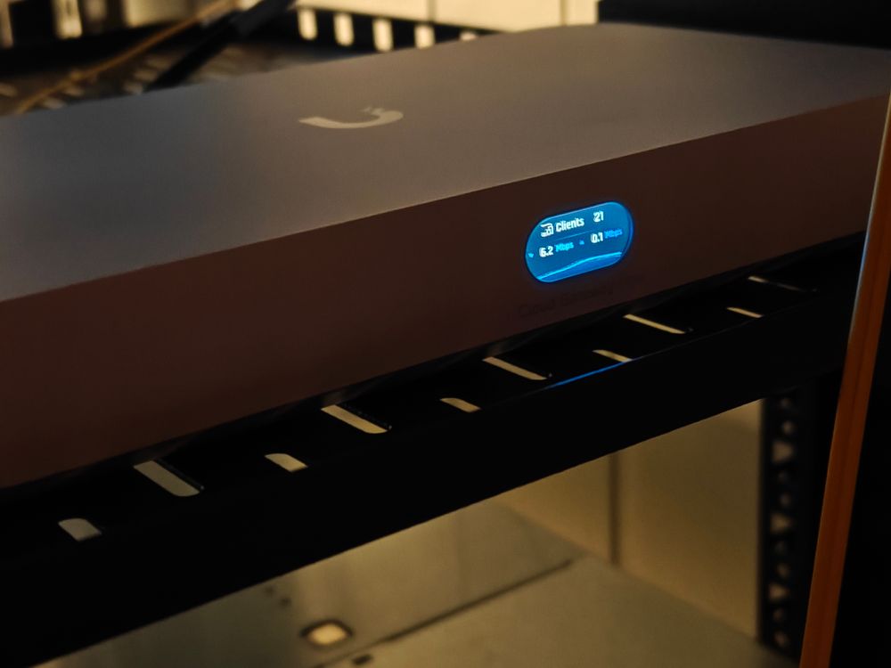 A close-up of an Ubiquiti Fiber Cloud Gateway device, sat on a shelf in a server rack.