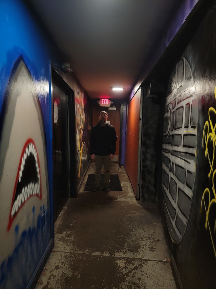 Dan standing in a dimly lit long hallway