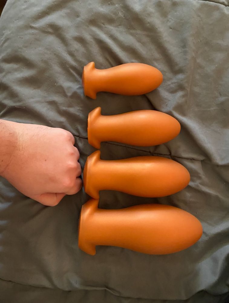 A picture of a fist and 4 buttplugs from small to extra large
