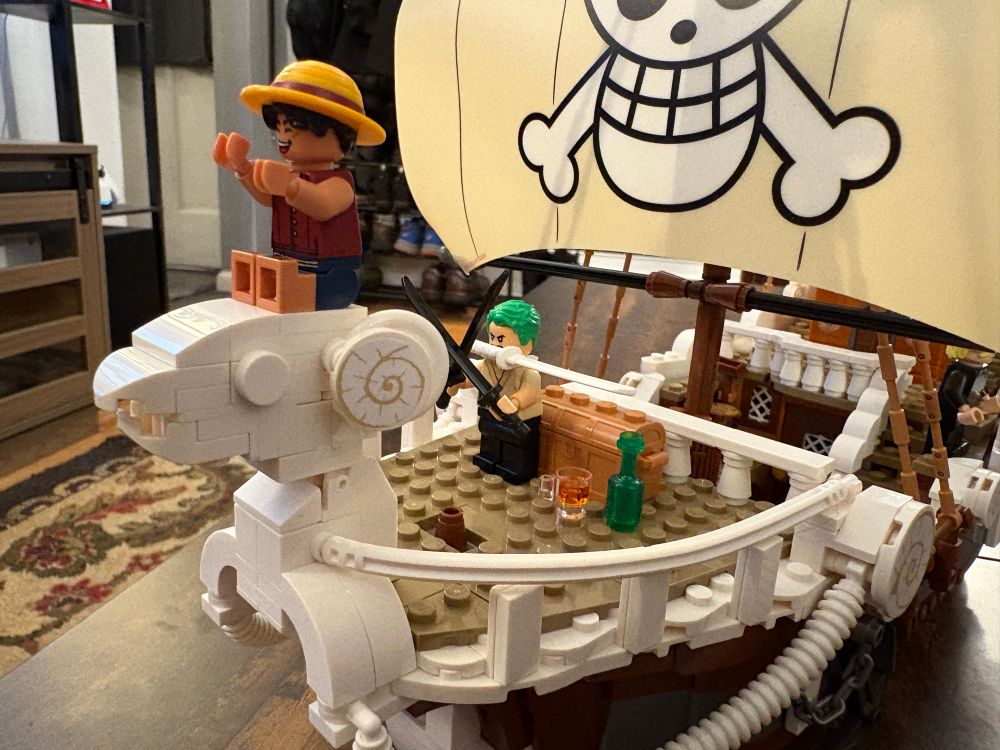 A close up of the One Piece Going Merry Lego set featuring Luffy sitting on the figurehead and Zoro sitting in the bow 