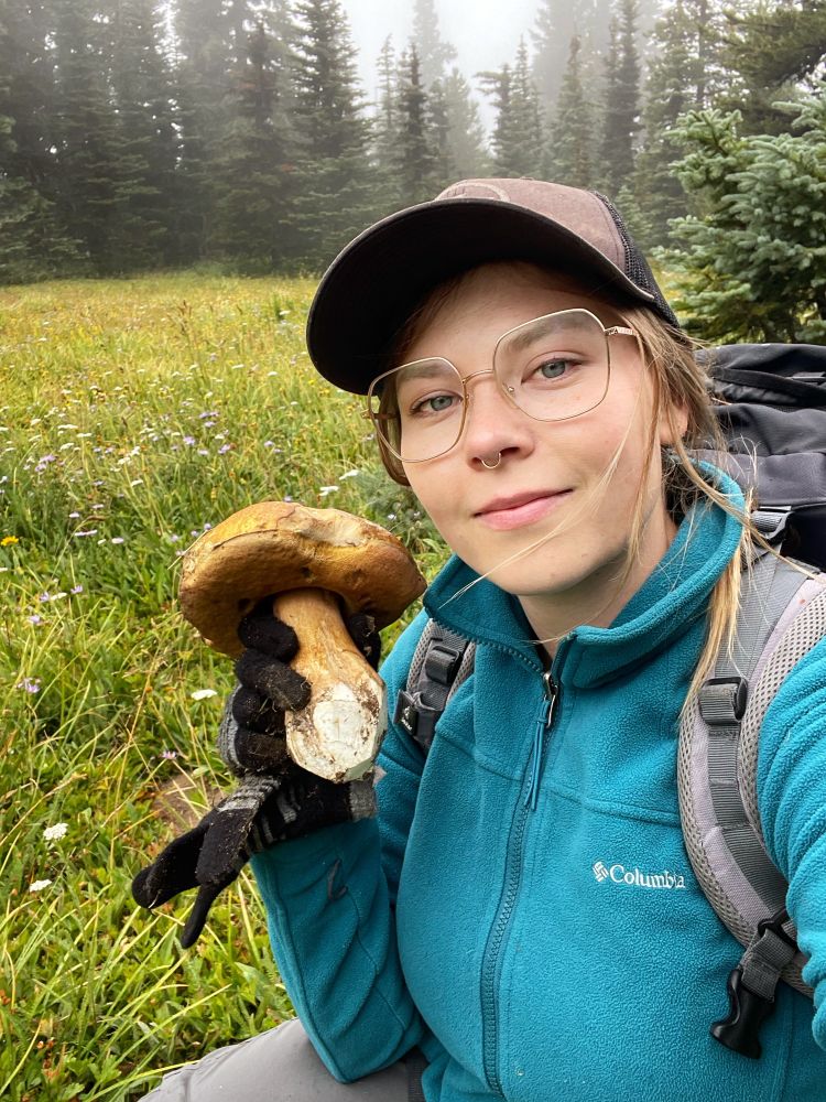 Selfie of a woman holding a mushroom in a Misty meadow. 