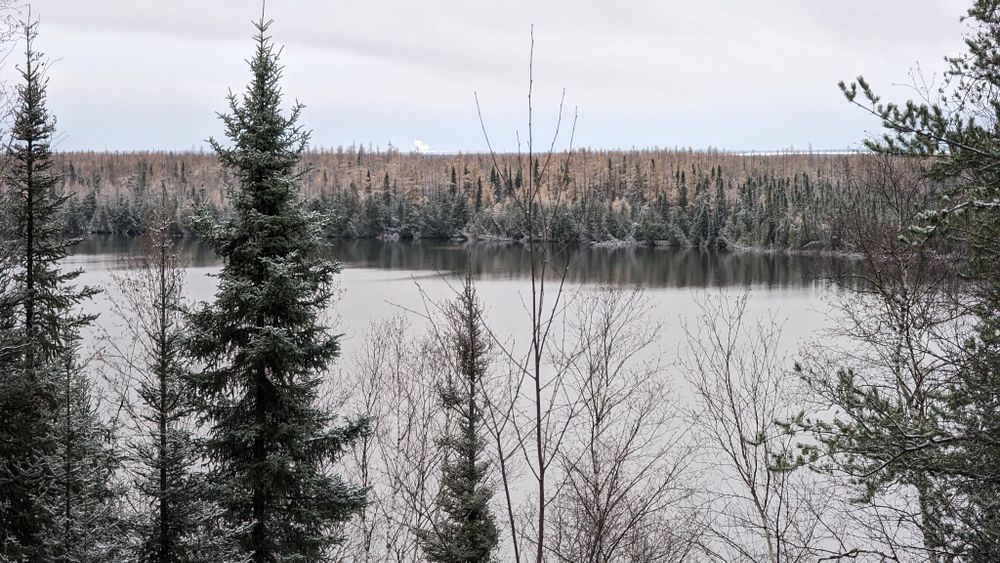 Taken from an elevated road overlooking Ice Chest Lake with a horizon lined with snow covered conifers.