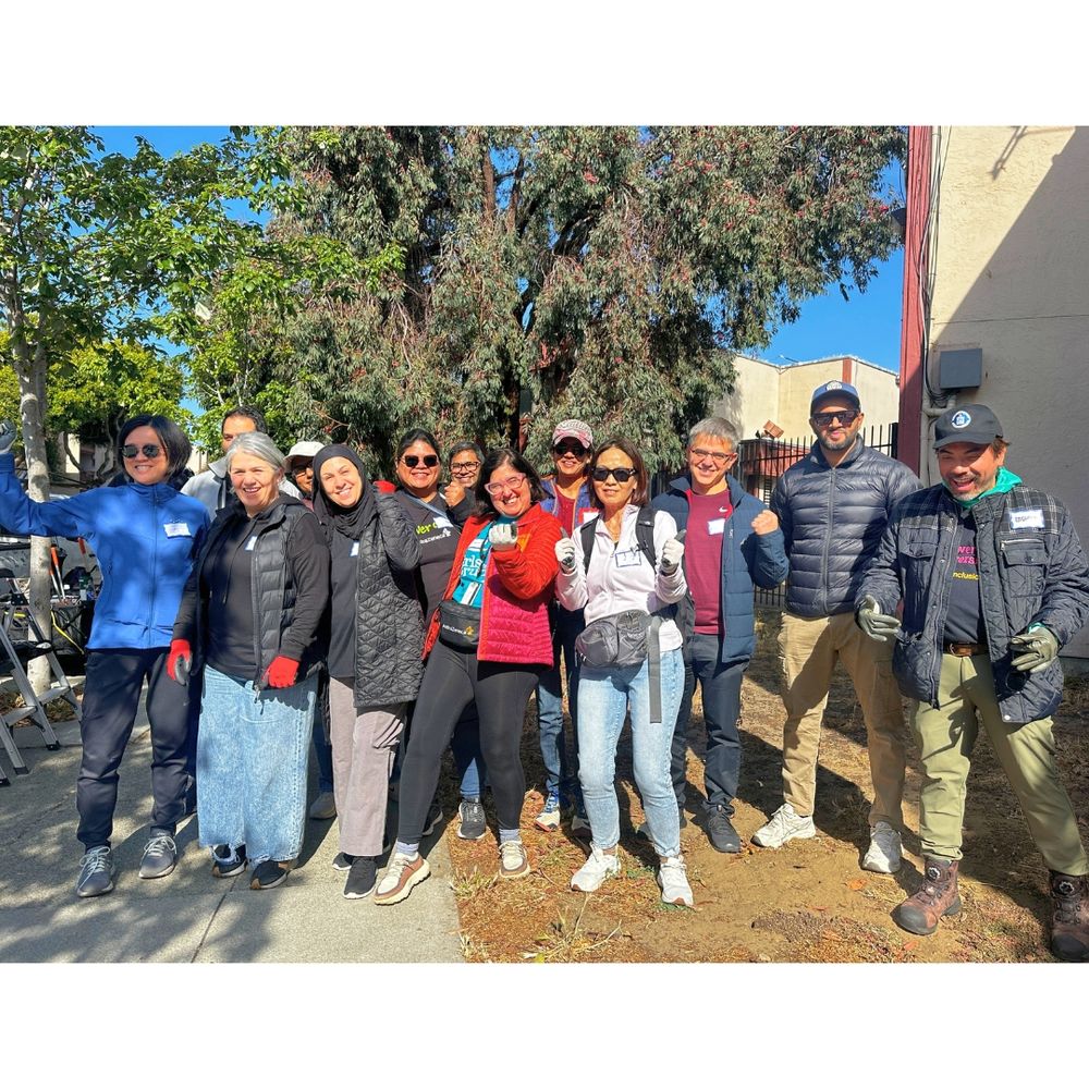Group photo of 13 smiling tree care volunteers.
