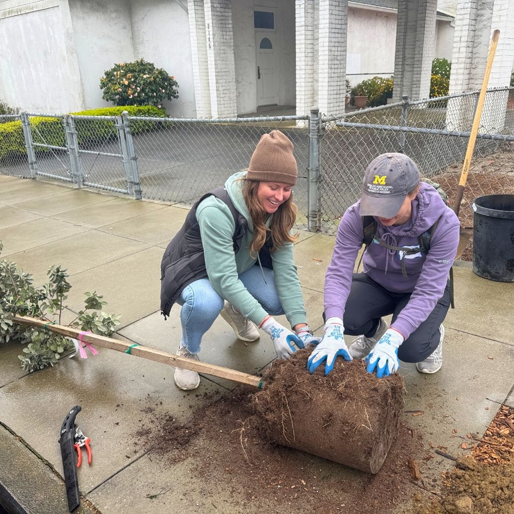 Two volunteers prepare a tree to be planted.
