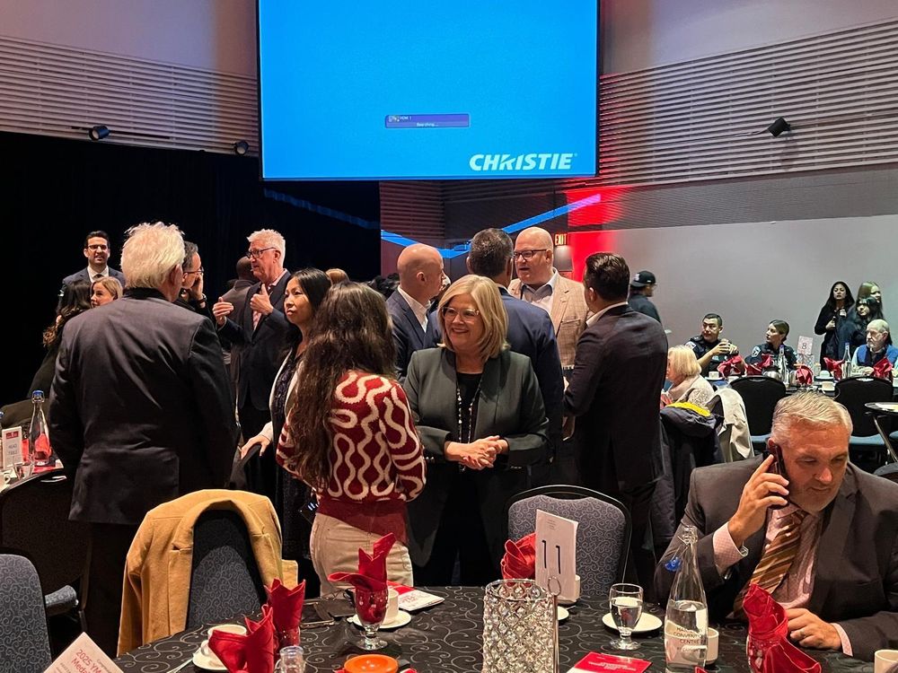 Mayor Horwath and others at the YMCA peace medal breakfast this morning standing in a room talking