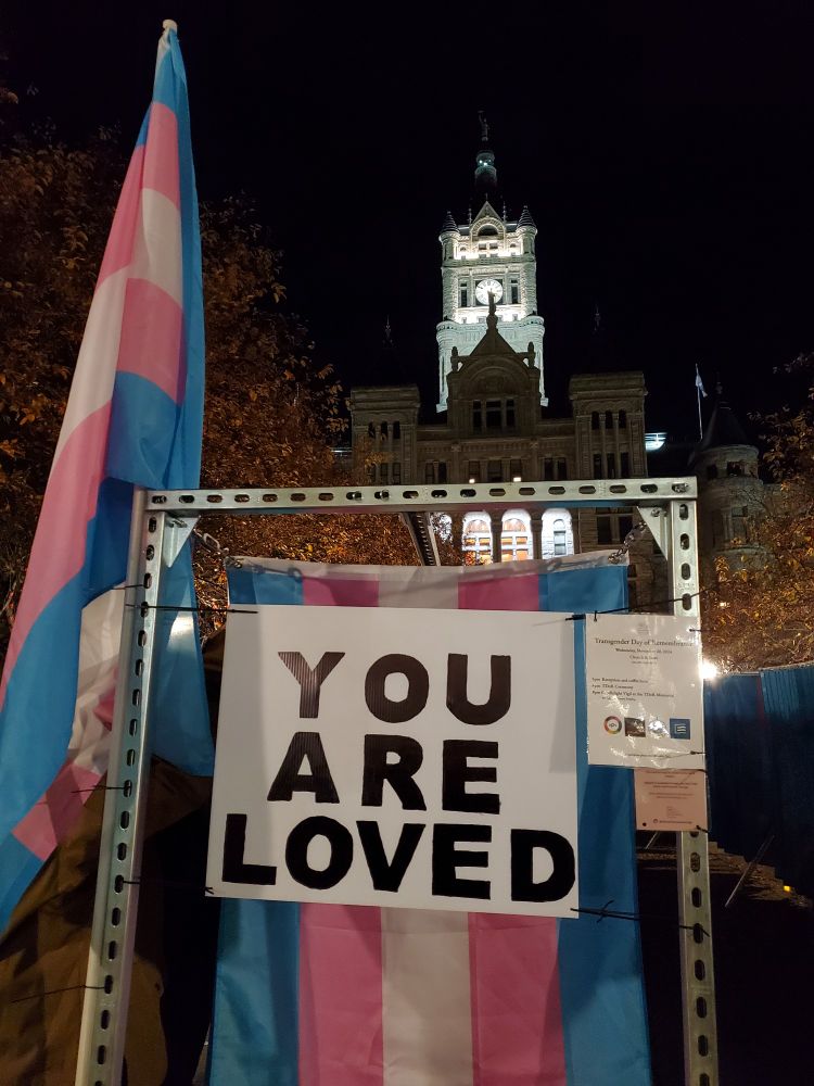 The trans flag with a sign that says "You are loved", in front of the City&County building in Salt Lake City.