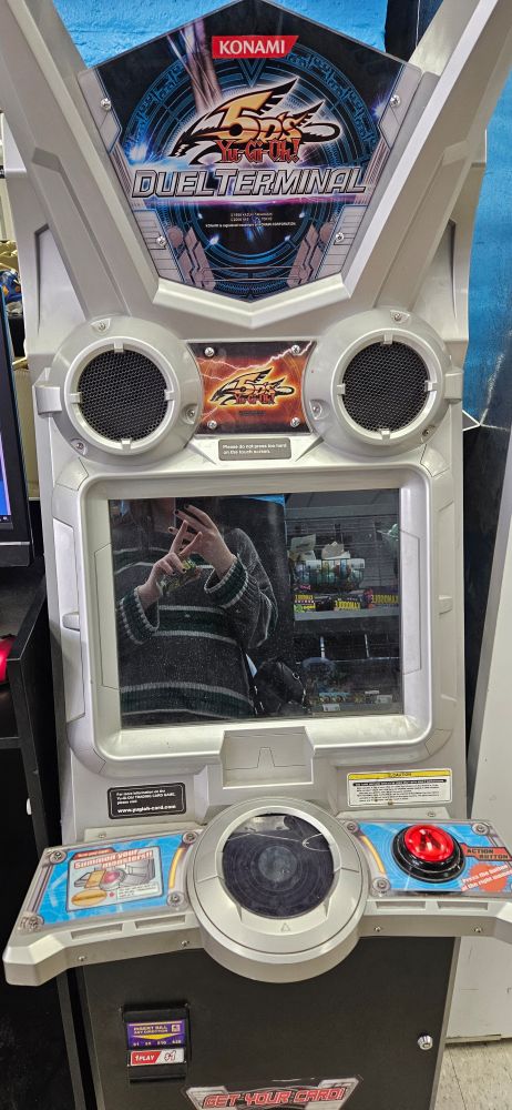 Picture of a yugioh duel terminal machine with Cherri reflecting on the screen
