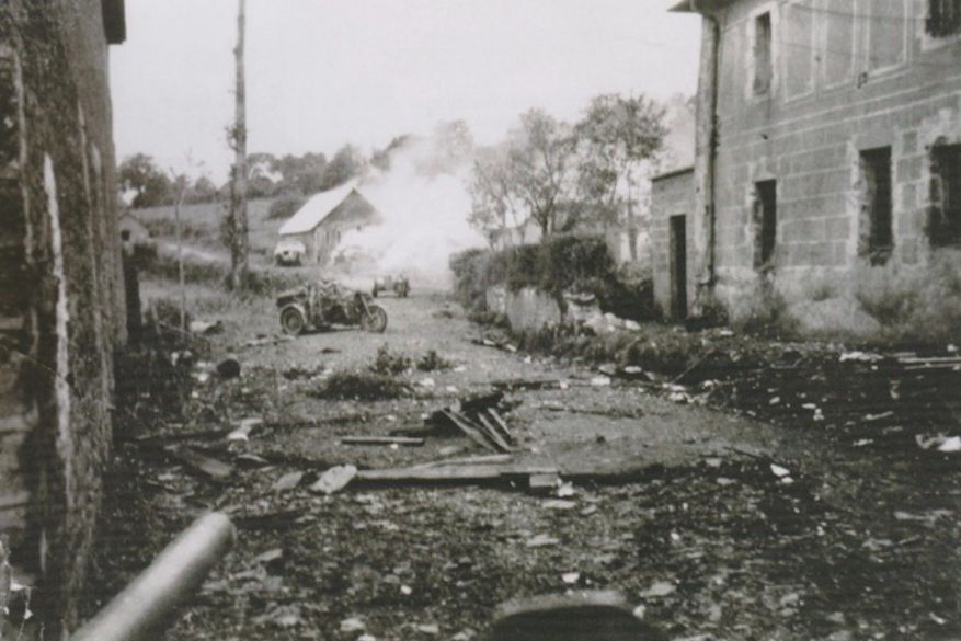 B/W photo taken in 1944. The barrel of a 57mm gun is facing two knocked out German motorcycle combinations and two similarly redundant SdKfz251 half tracks. 
Le Pont Brocard.