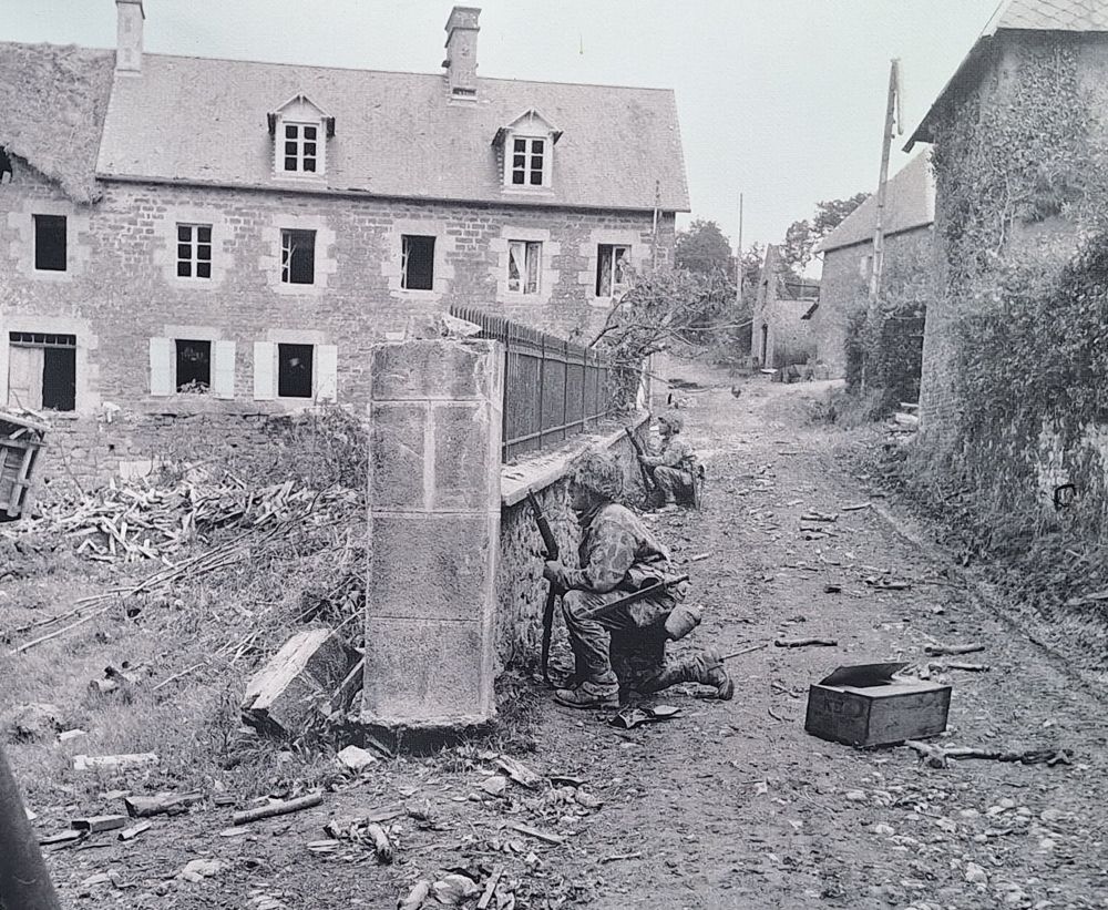 Soldiers from US 2nd Armd Div hiding behind a wall in le Pont Brocard.