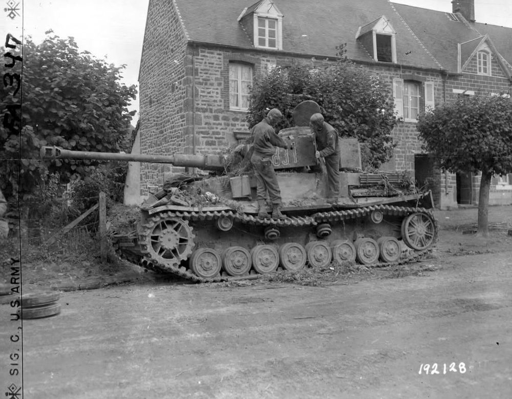 B/W photo of a knocked out German PzIV with two American tank crew examining it