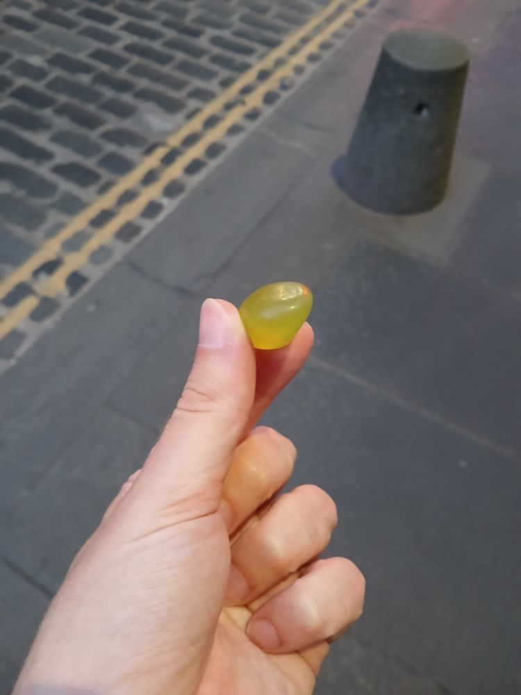 Professional actor Jason Thurston holds a green gemstone in his left thumb and forefinger on the Royal Mile in Edinburgh.