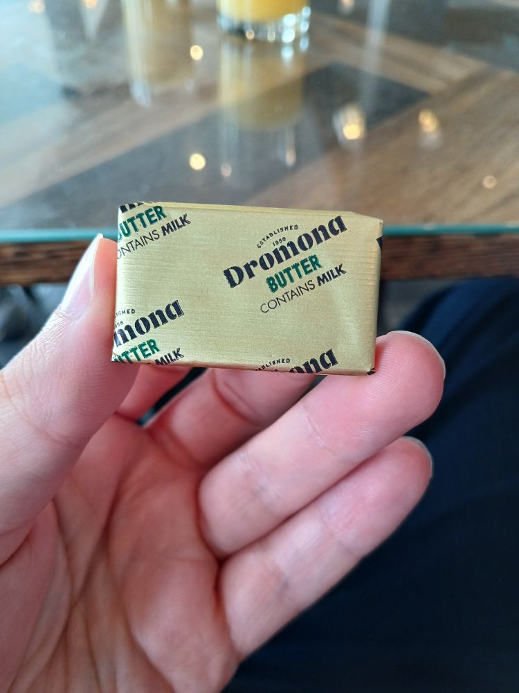 Professional actor Jason Thurston holds a packed of Dromond butter in his left hand at a breakfast table.