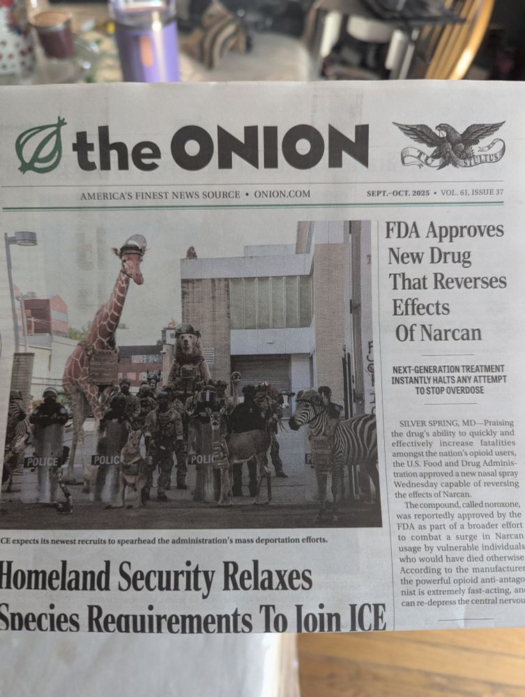 Physical copy of The Onion with headlines "FDA approves new drug that reverses the effects of Narcan" and "Homeland Security relaxed species requirements to join ICE" visible