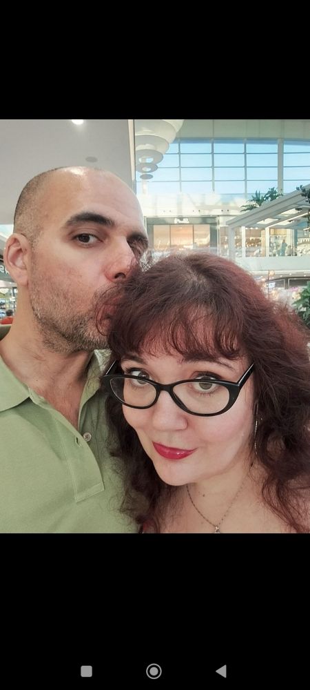 Un tío rapado dándole un beso en la cabeza a tremenda pelirroja con gafas guays. 