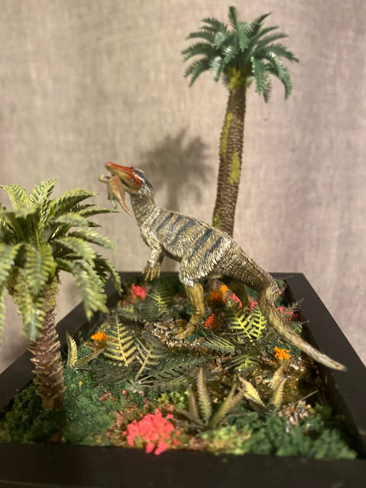 Feathered Dinosaur in a foliage rich river bed biting down on a baby Sauropod it snatched up from the ferns before it could escape 