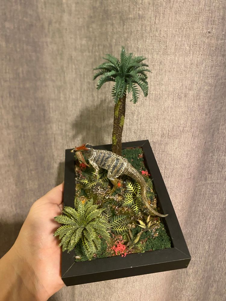 Feathered Dinosaur in a foliage rich river bed biting down on a baby Sauropod it snatched up from the ferns before it could escape 