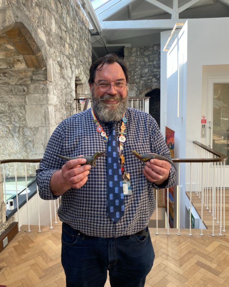 Smiling professor holding two Dinosaurs 