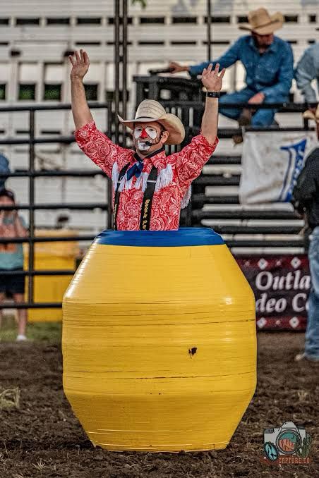Rodeo clown emerges from a barrel. 