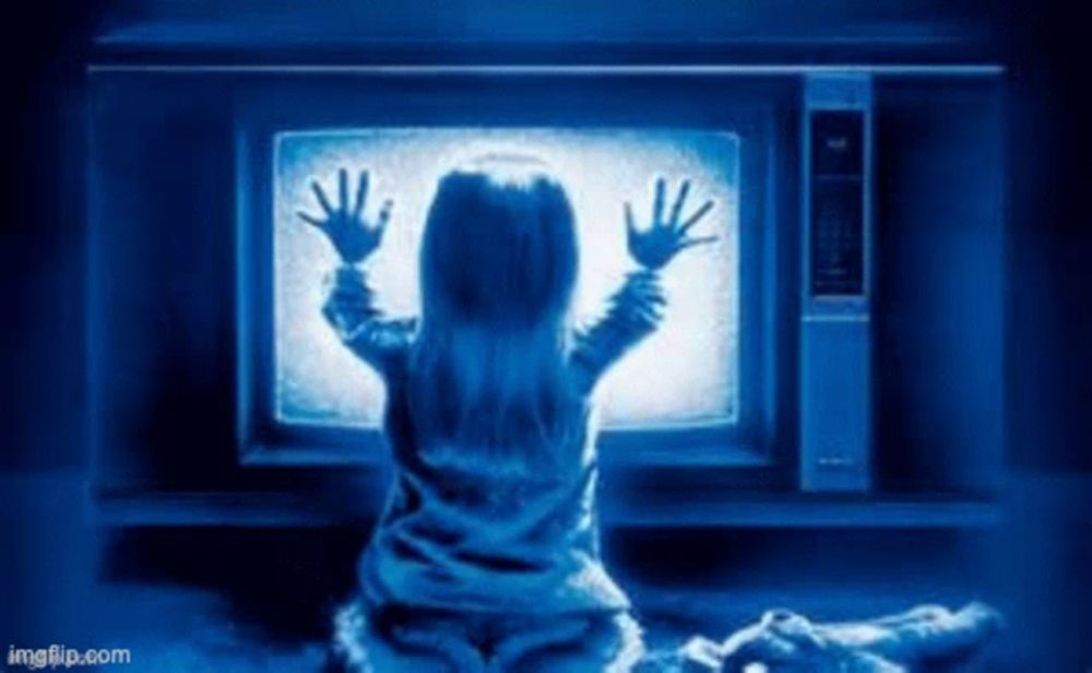 a girl is sitting in front of a television with her hands up .