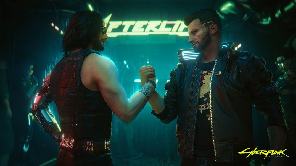 Male V and Johnny Silverhand lock their hands together in front of the entrance to Afterlife, with its neon sign glowing in the background. The Cyberpunk 2077 logo is printed in the bottom right corner.