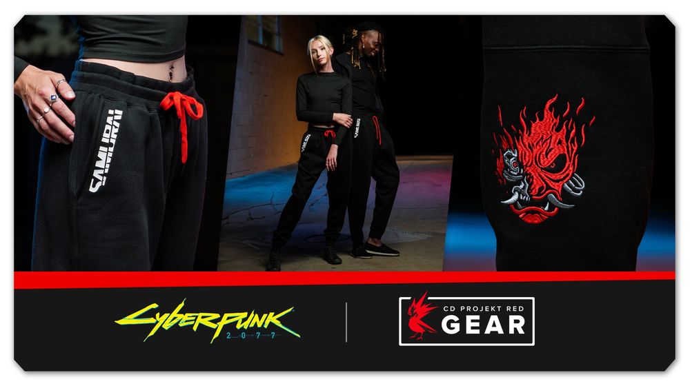 Two models pose in a large, dark room, each wearing black outfits including joggers decorated with Cyberpunk 2077 detailing. They feature a red drawstring, the name Samurai in thick white letters over the side seam pockets, and the Samurai logo in red, which depicts a red oni mask with cybernetic implants. Cyberpunk 2077 and CD Projekt Red Gear logos are stamped at the bottom.