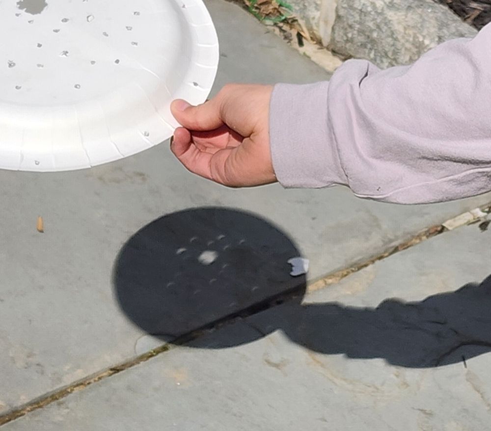 Eclipses through a child's hole filled paper plate