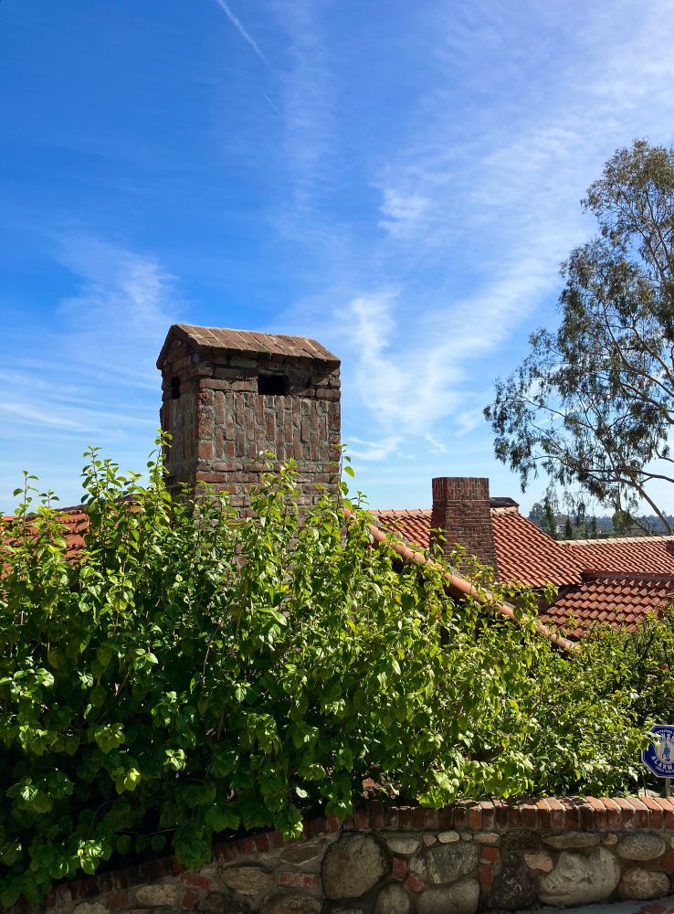 Answer: Heart of Los Angeles, California

Historic brick chimneys rise up over clay roof tiles. Greenery and blue sky surround them. 