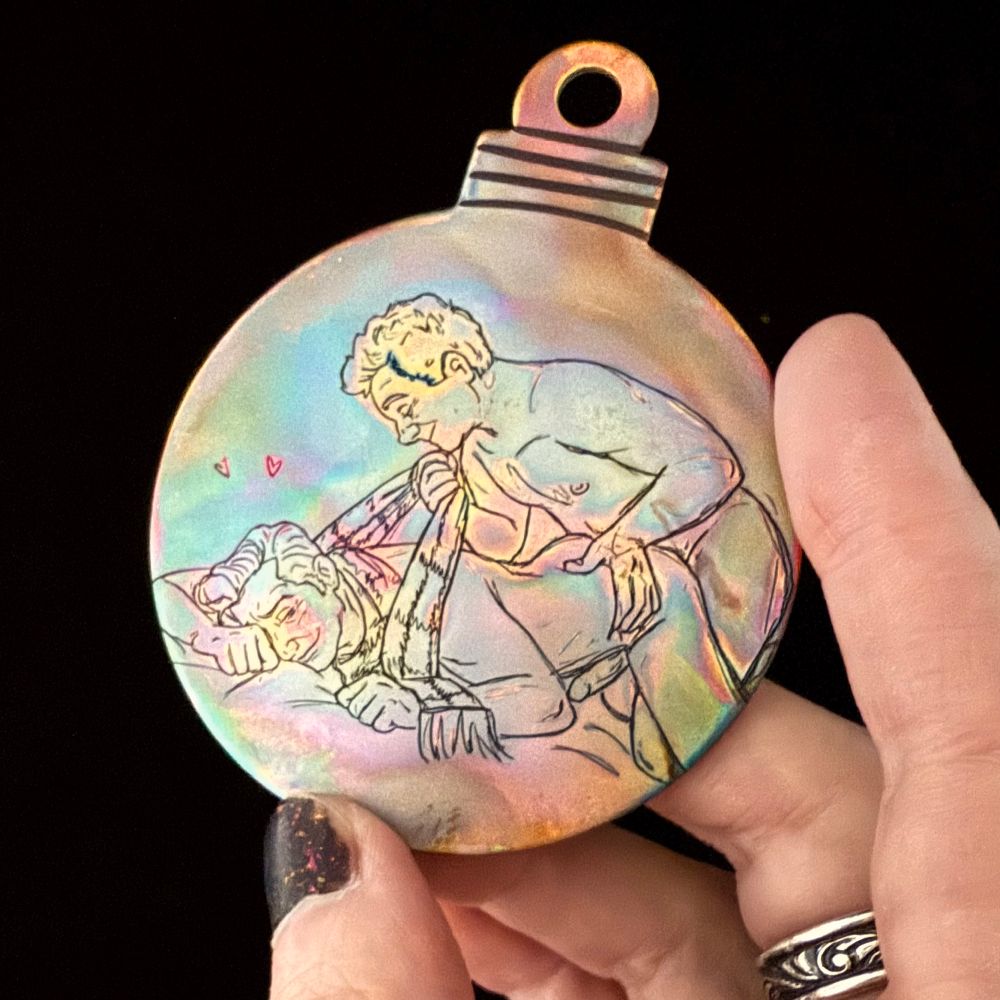 A hand holding a copper ornament against a black background. The copper is engraved with a sketch of Aziraphale and Crowley having sex: Crowley is lying on his chest with his hips tilted upward as Aziraphale kneels behind him, leaning down with one hand grabbing his hip and the other tugging the tartan scarf around his neck. The copper has a colorful heat patina in pastel colors reminiscent of an oil slick.