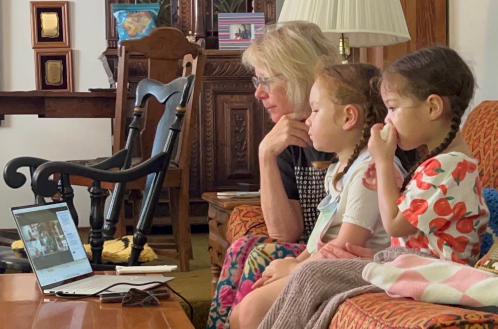 A grandmother and two cute granddaughters looking at a laptop zoom meeting 