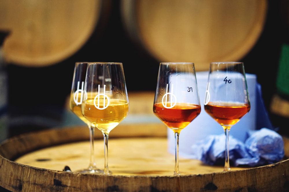 Glasses of beer of various colours on a wooden barrel, with a roll of blue paper roll behind them