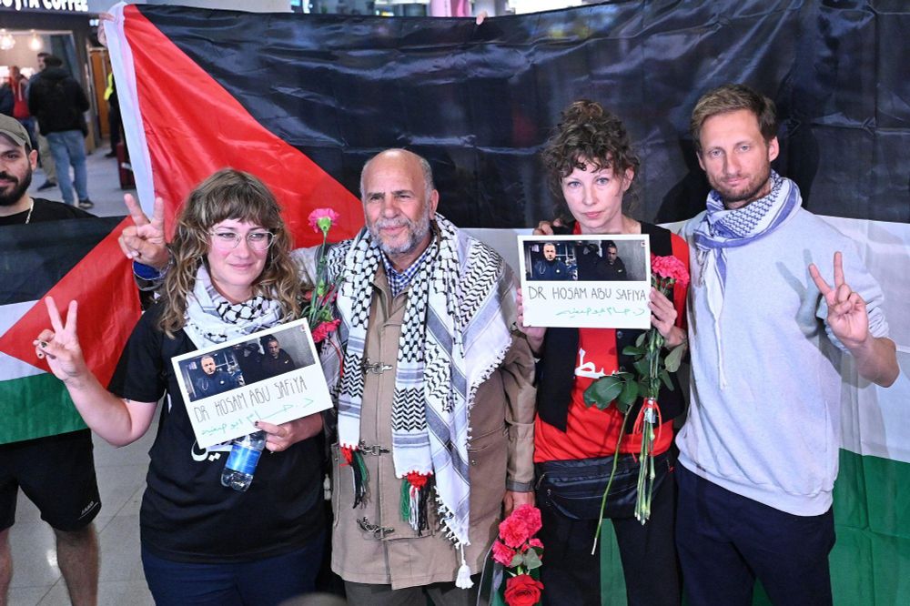 Group photo of the Polish delegation in front of a Palestinian flag. Starting from the left: Ewa Jasiewicz, Omar Faris, Nina Ptak, Franciszek Sterczewski