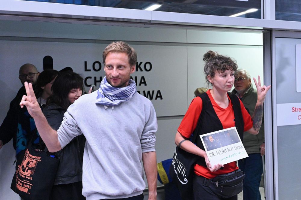 Franciszek Sterczewski and Nina Ptak entering the airport, showing peace signs.