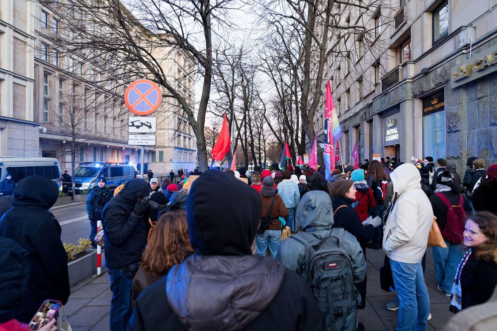 Tłum ludzi stojący na chodniku przed ministerstwem. 
