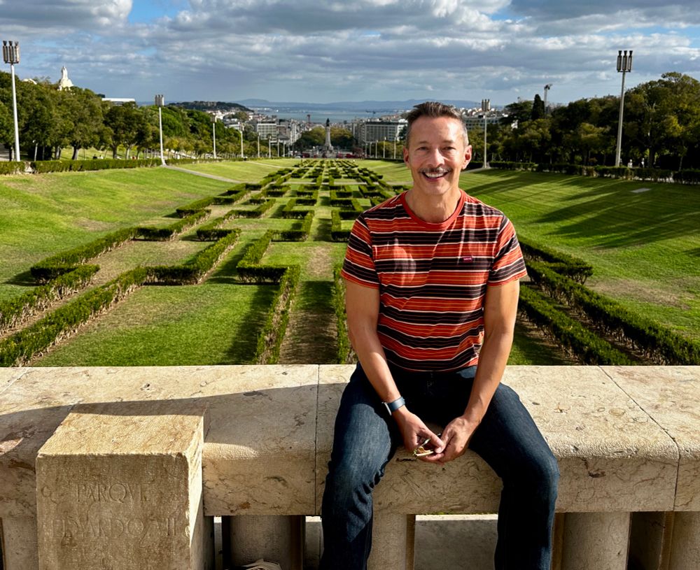 Me in the same spot 19 years later. I’m wearing a striped orange tshirt, a moustache and a smile. 