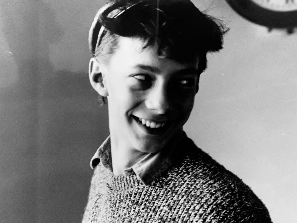 A black and white photo of me at 17. I’m wearing a baggy grey jumper and for some reason a leather cap. 