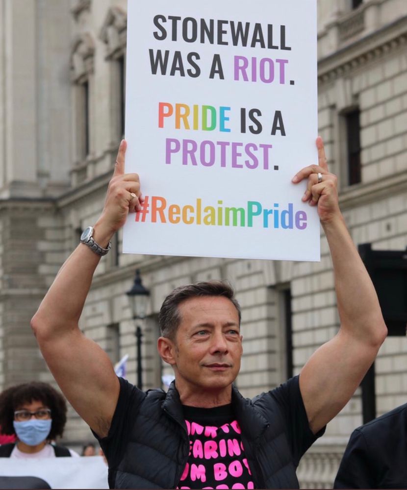 Me on the Reclaim Pride March in 2022 holding a placard that reads ‘Stonewall was a riot
Pride is a protest’.
My arms are large and my hair awesome. 