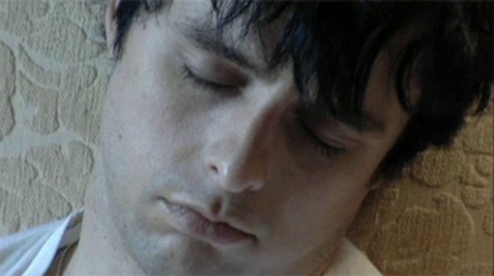 a close up of a man 's face with a white shirt on