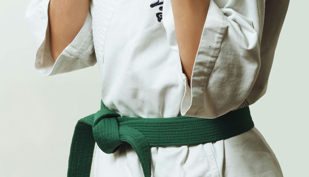 A person wearing a white martial arts uniform and a green belt
